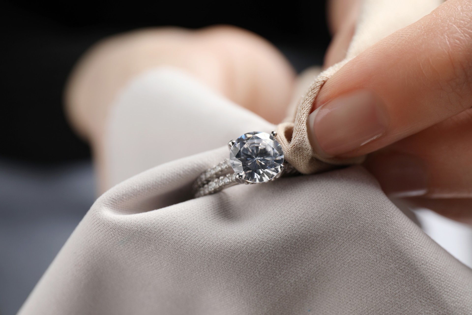 Jeweler cleaning diamond ring with microfiber cloth, closeup